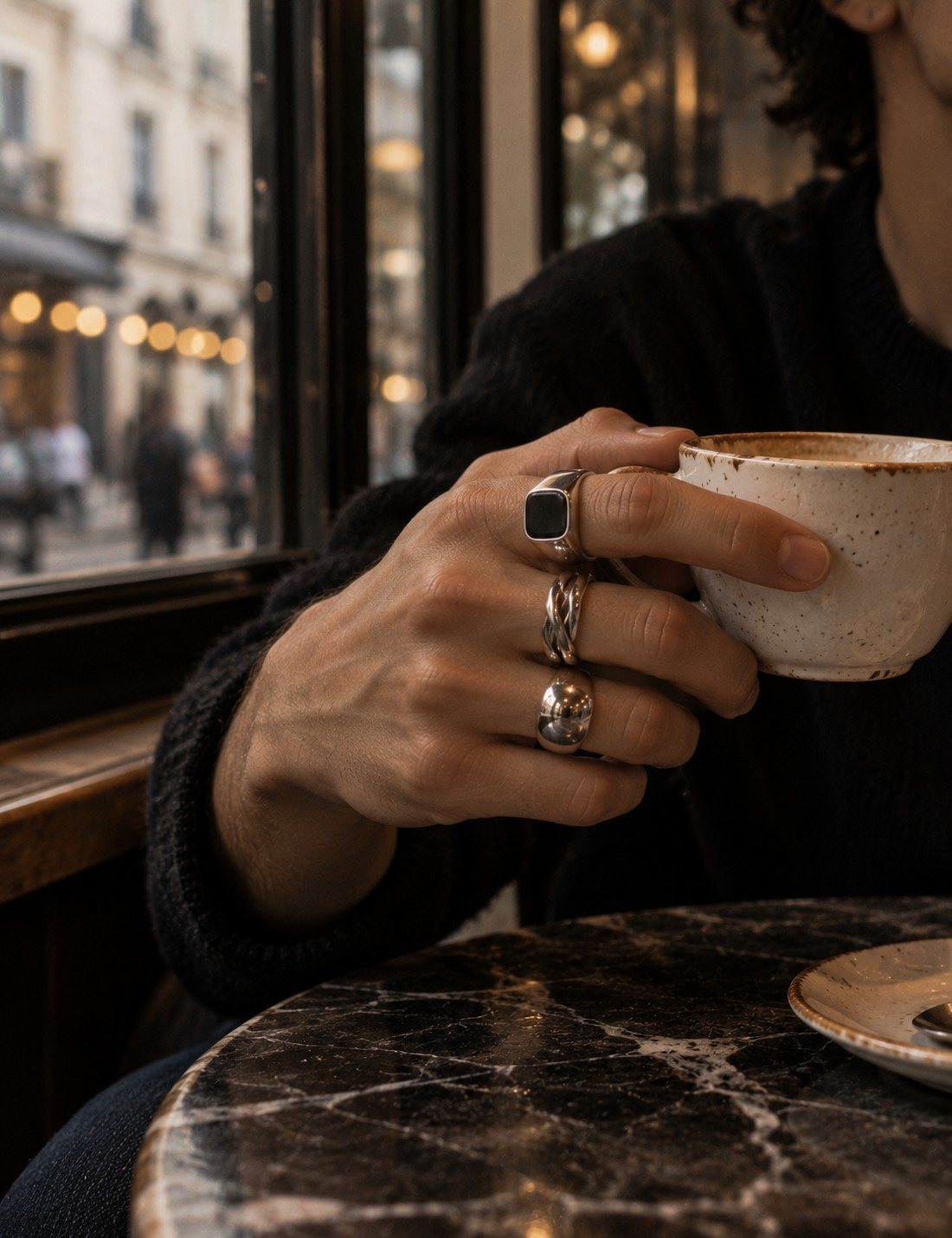 Hand with a signet, a braided band and a dome ring holding a coffee cup