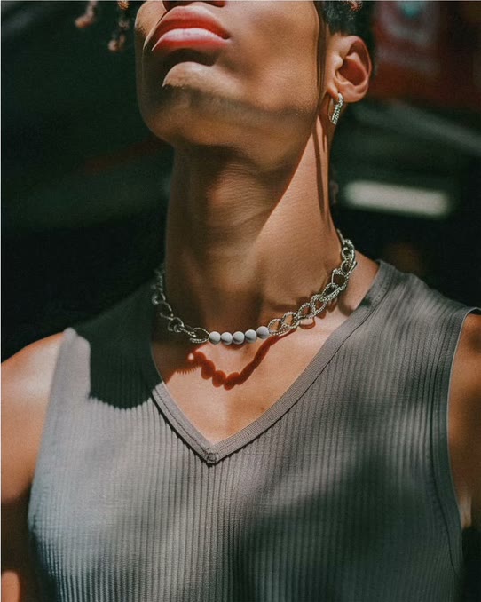 Model in a ribbed tank wearing a chain and pearl choker