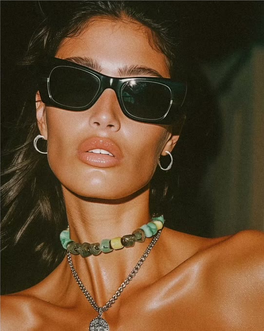 Model in sunglasses wearing a beaded choker and pendant