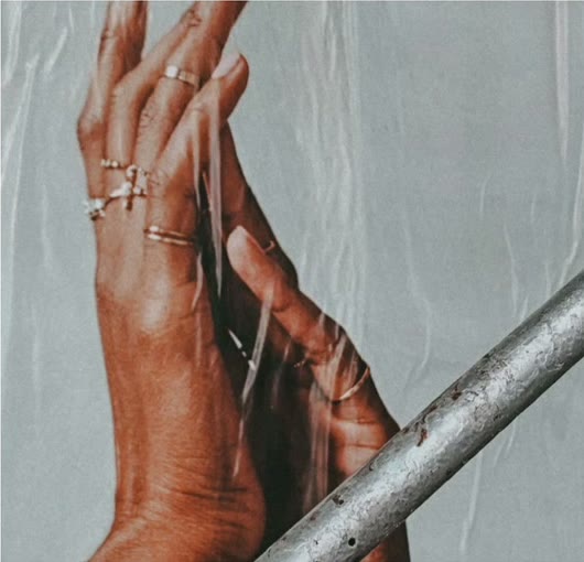 Hands with stacked silver rings against a pale wall